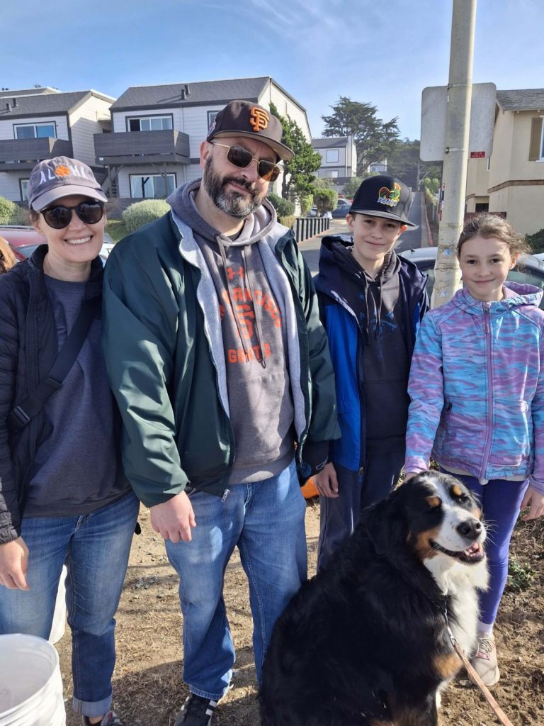 A family of four and a dog at a beach cleanup