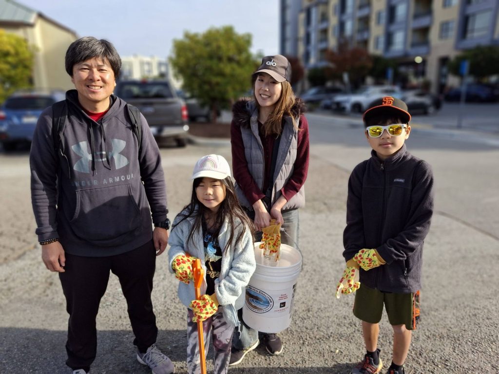 A family poses with their trash pickers and buckets during a community cleanup