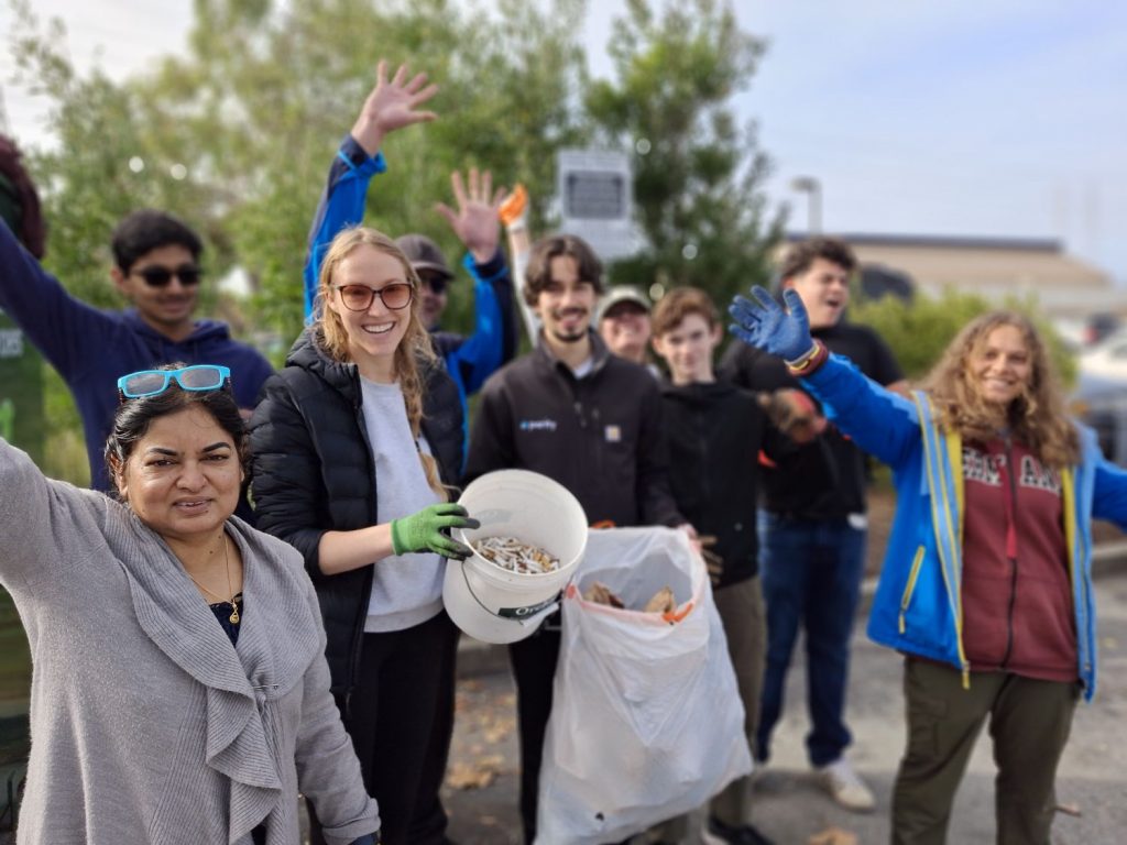 Volunteers hold a bucket of cigarette filters and a bag of trash picked up during a cleanup