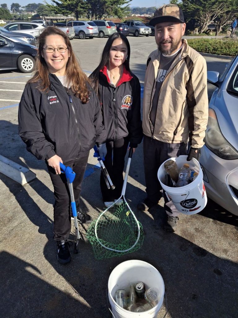 Three volunteers pose with buckets of trash