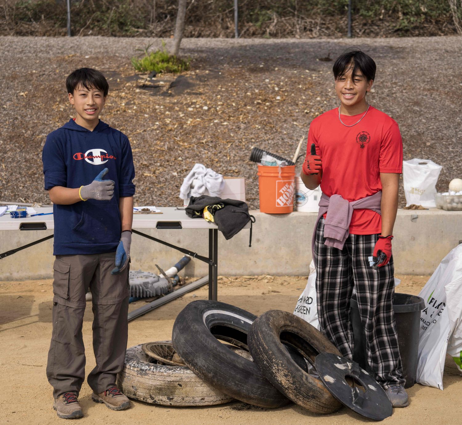 Two young volunteers pose with tires found during a cleanup event