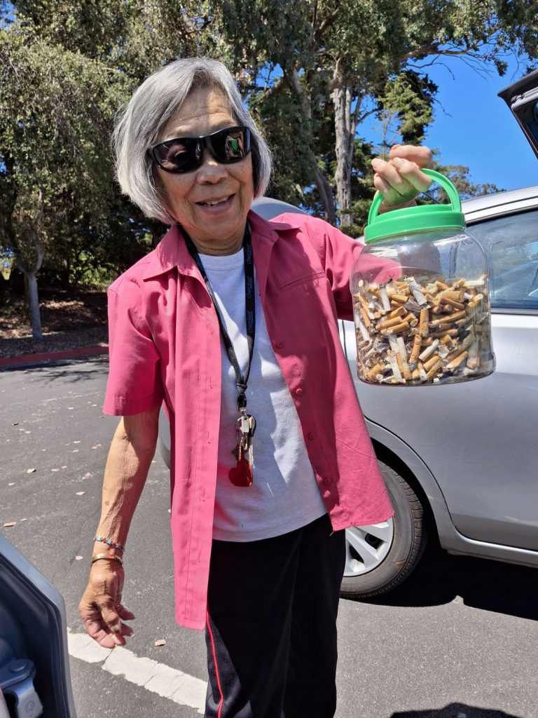 A female volunteer holds a container filled with cigarette filters collected to be recycled