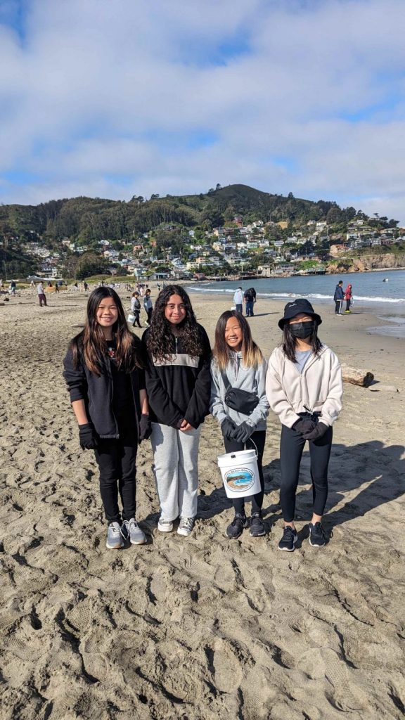 Four young volunteers show off the trash collected at a beach cleanup