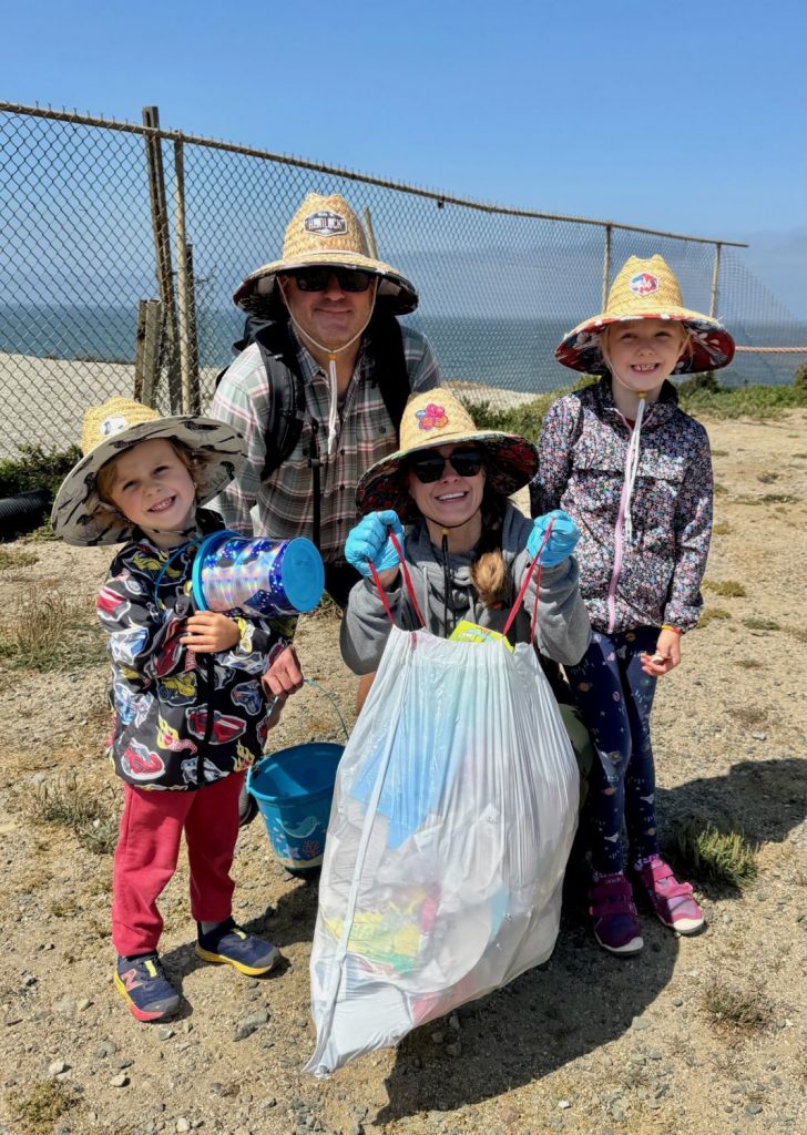 A family of four shows off the trash collected during a beach cleanup