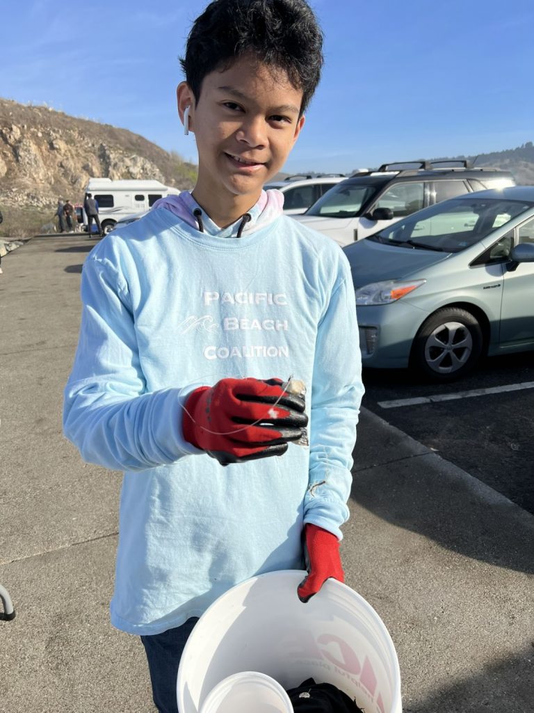 A teen showcases the fishhook found at a beach cleanup