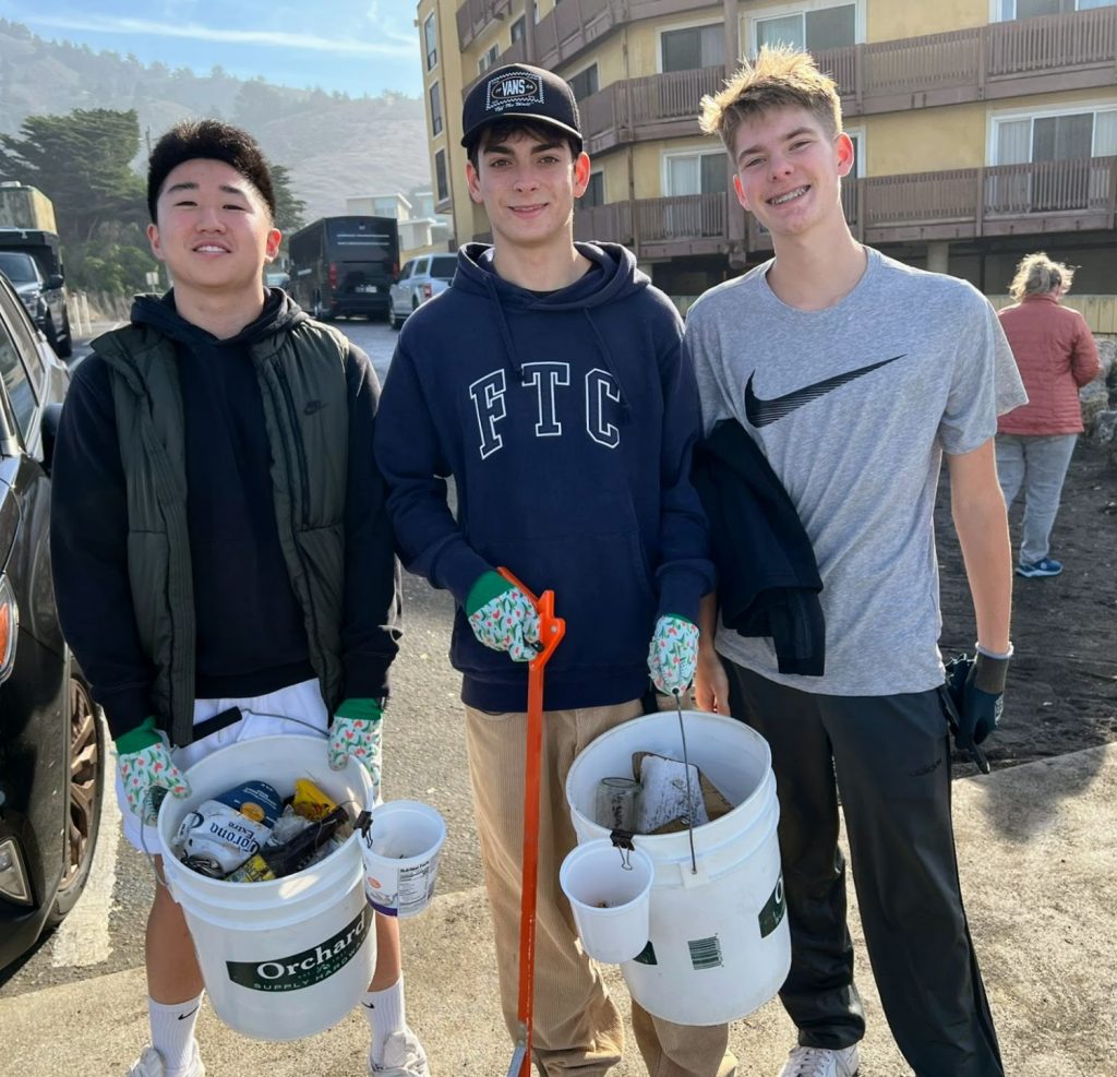 Three teens showcase the trash that they collected during a beach cleanup