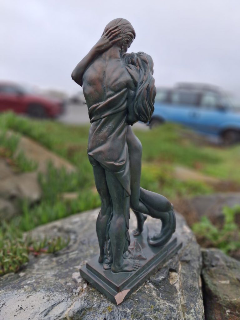 A tall statue of a couple embracing found at a beach cleanup