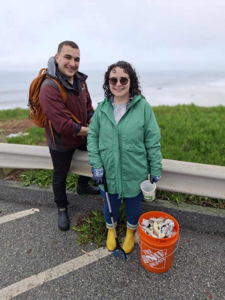 Two adult volunteers show off the trash that they collected during a yearend Pacific Beach Coalition beach cleanup