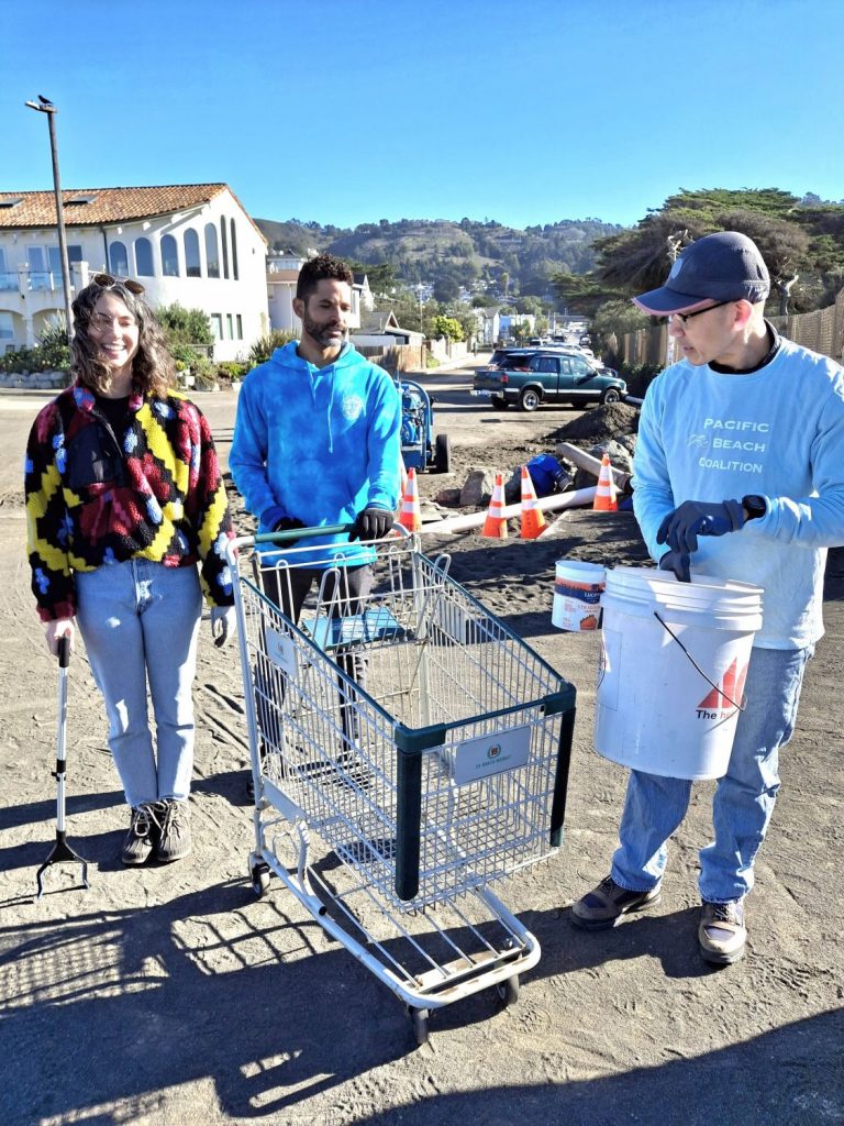 Volunteers stand near a shopping cart that was retrieved during a PBC cleanup event