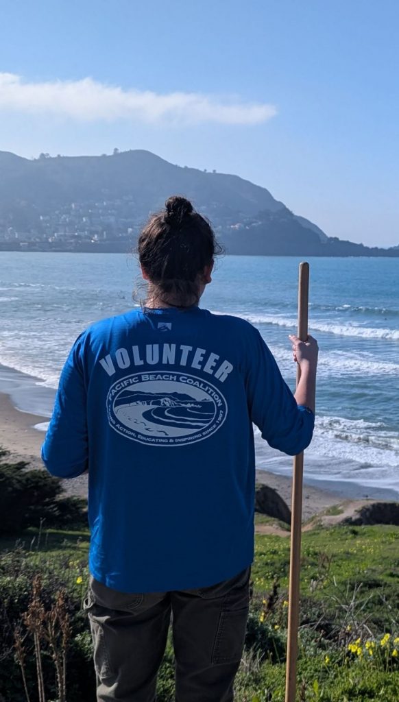 A PBC site captain poses with a shovel with the ocean in the background