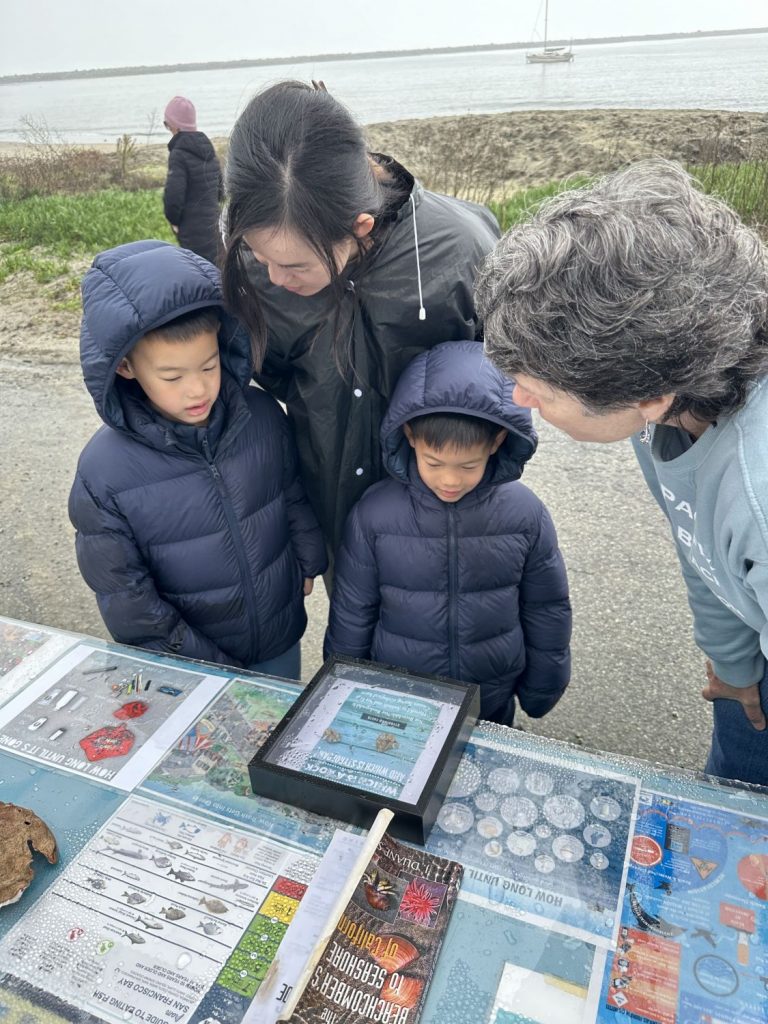 A family of three talks to a naturalist at a yearend beach cleanup