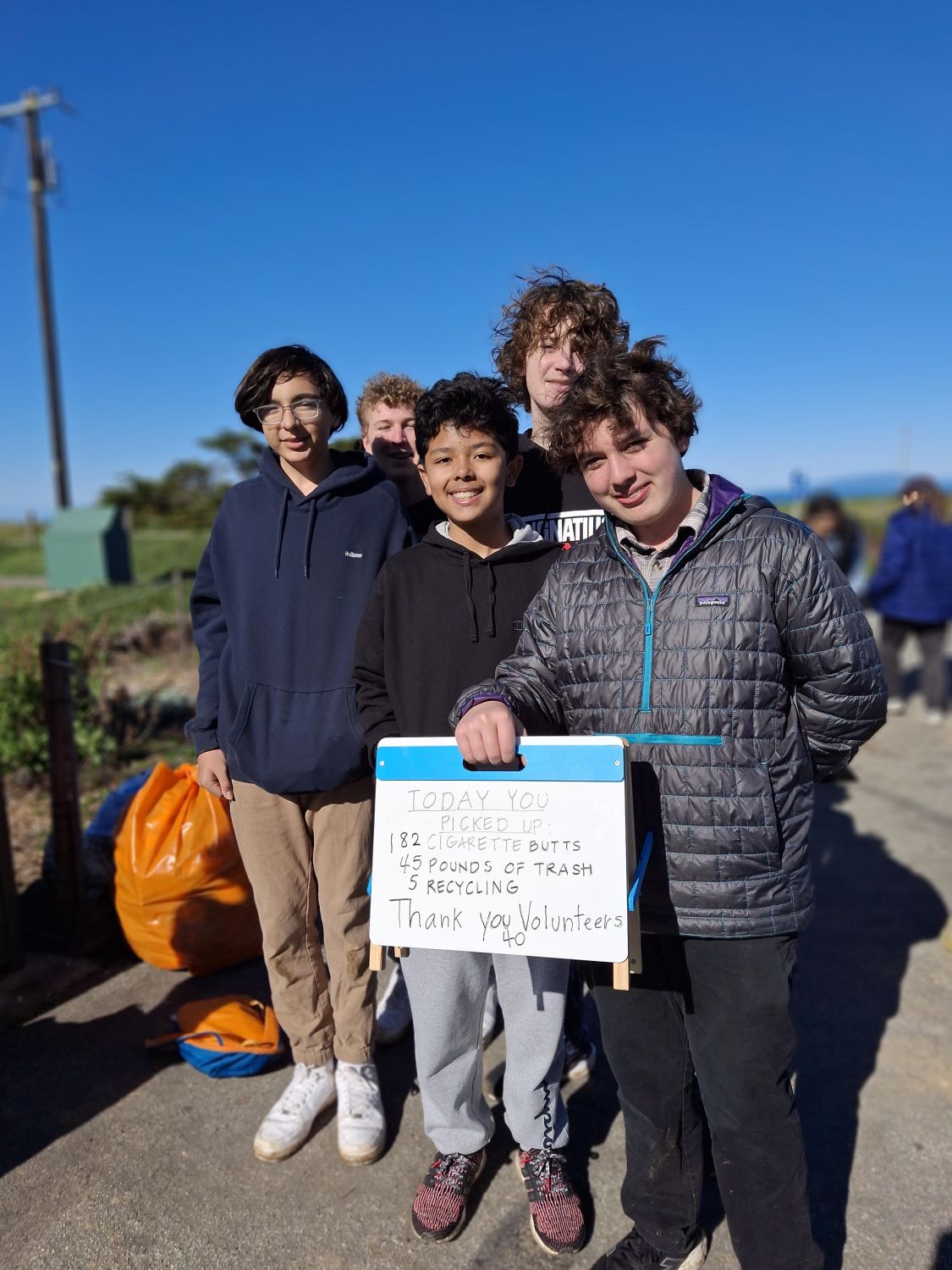 Five teen volunteers pose with a poster that displays results from a February 2025 PBC cleanup